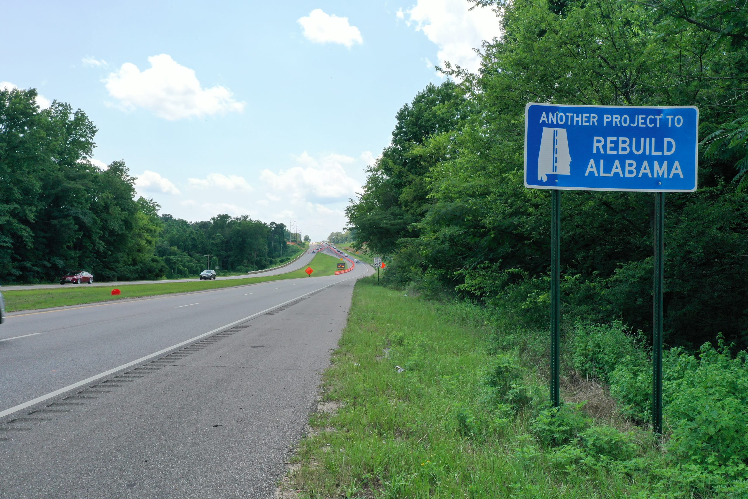 Rebuild Alabama road sign with greenery and roadway in the background