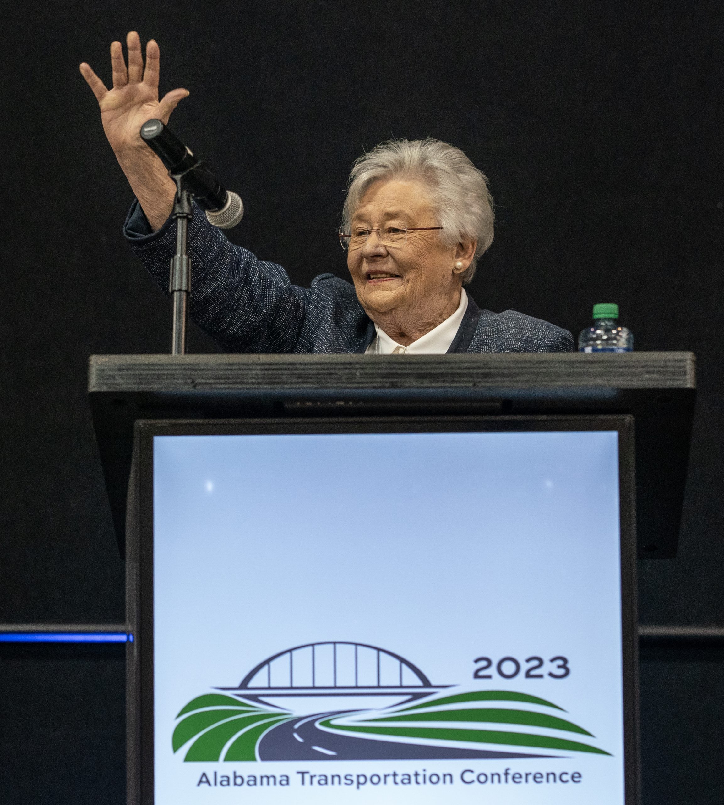 Governor Kay Ivey standing in front of a podium waving at the crowd