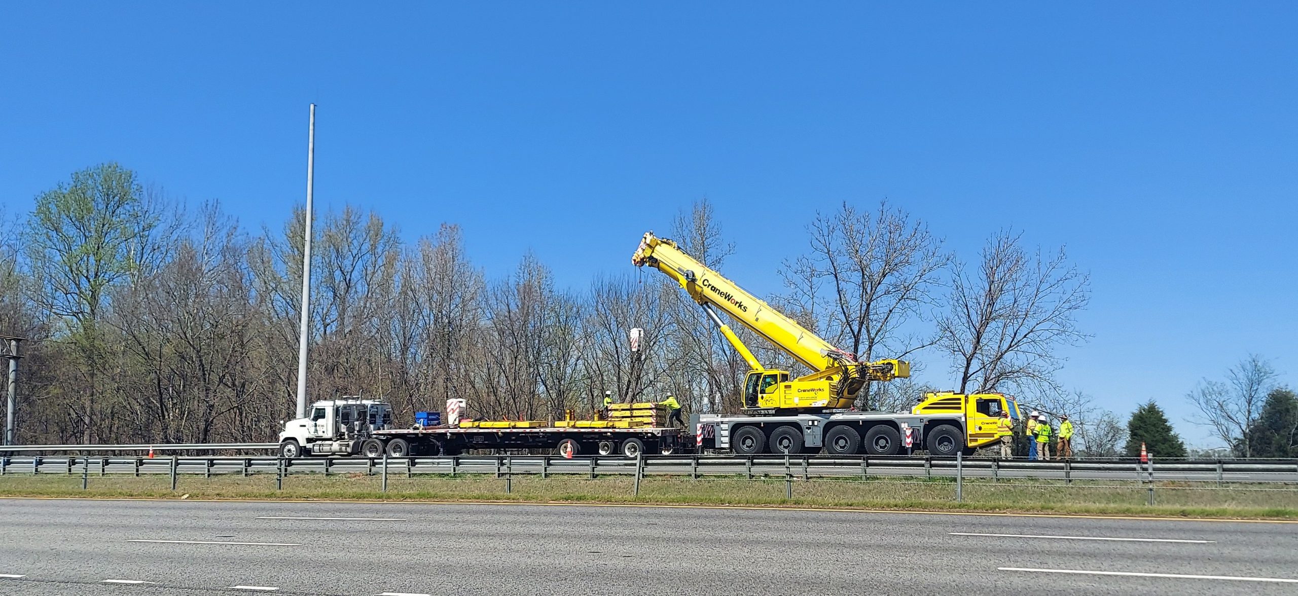 Workers install a concrete pole on I-565 near Mooresville Road in Limestone County for a future traffic camera on Tuesday.