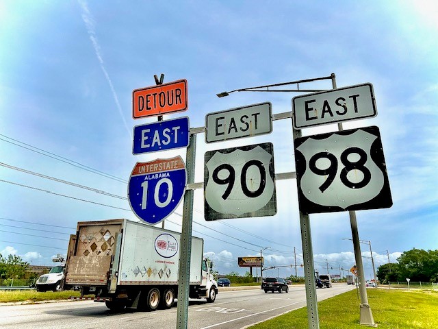 Vehicles traveling on the US 90 Causeway in Mobile, Alabama. Directional signs for US 90, US 98 and I-10 East.