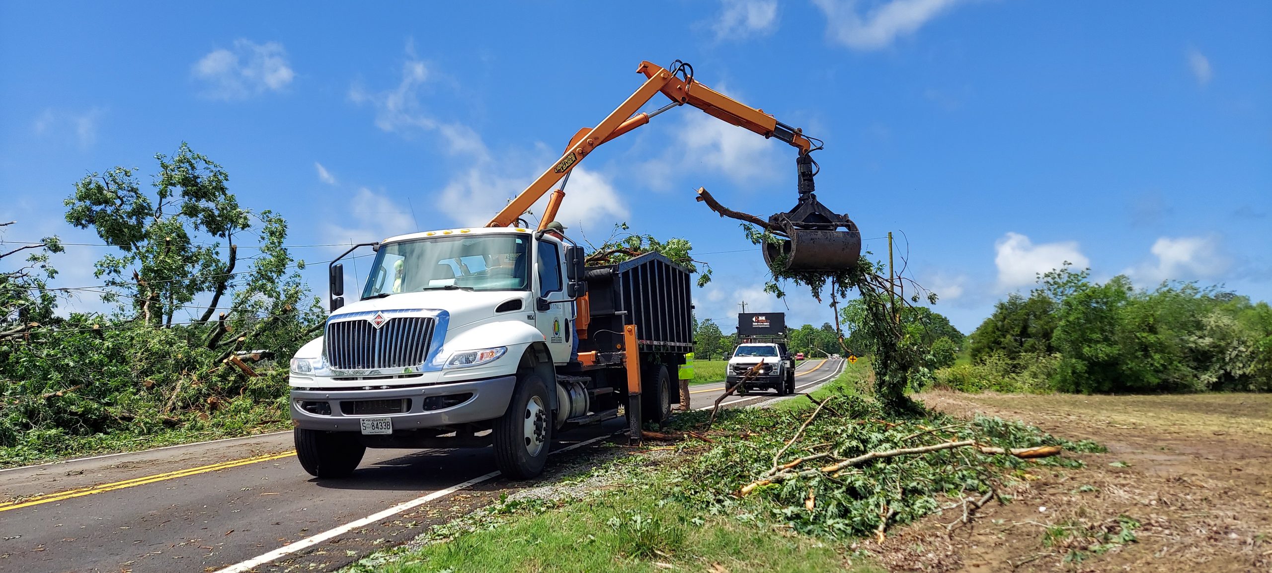 A grapple lifts tree limbs into an ALDOT brush truck.