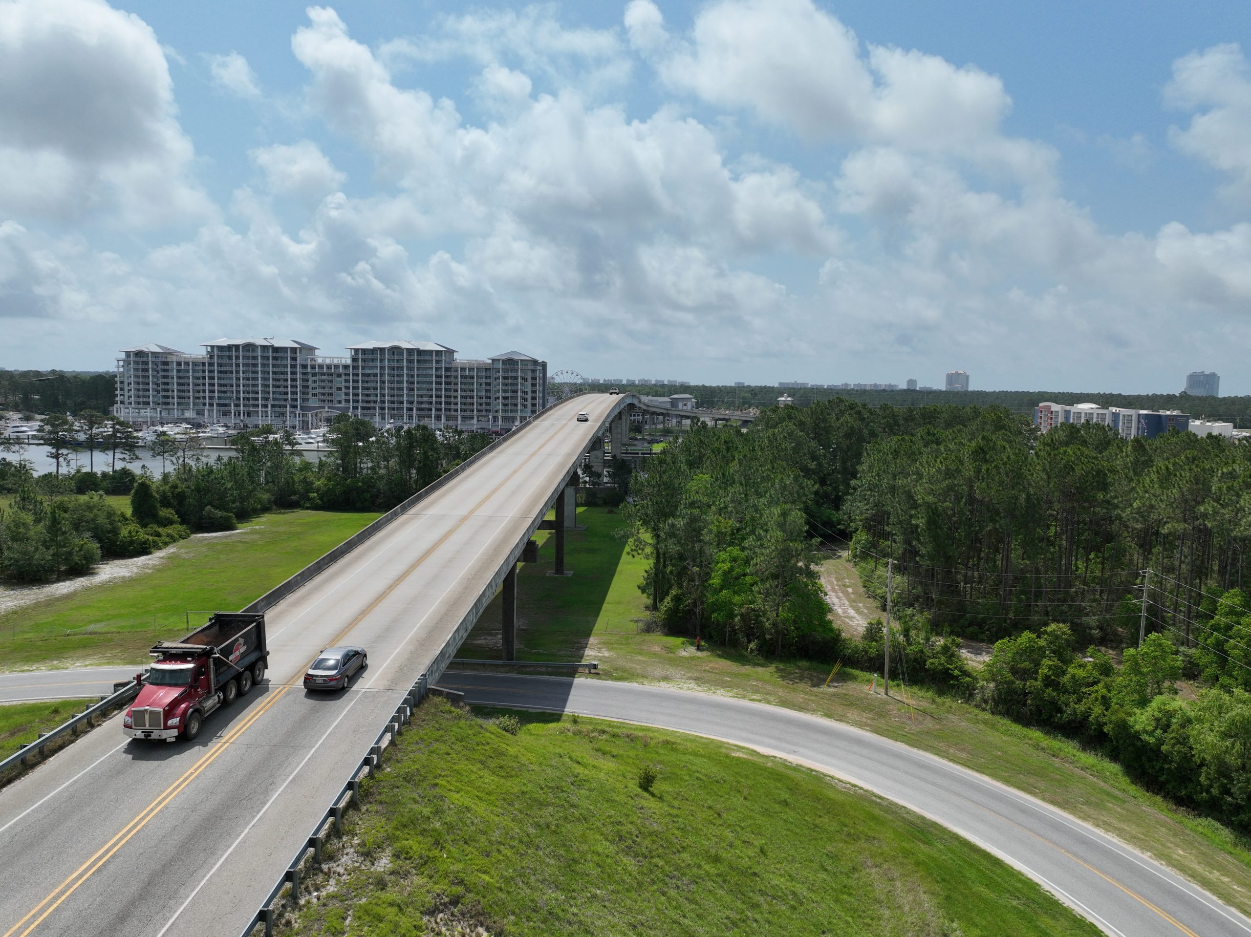 a commercial truck and passenger car cross over a bridge leading into coastal Alabama