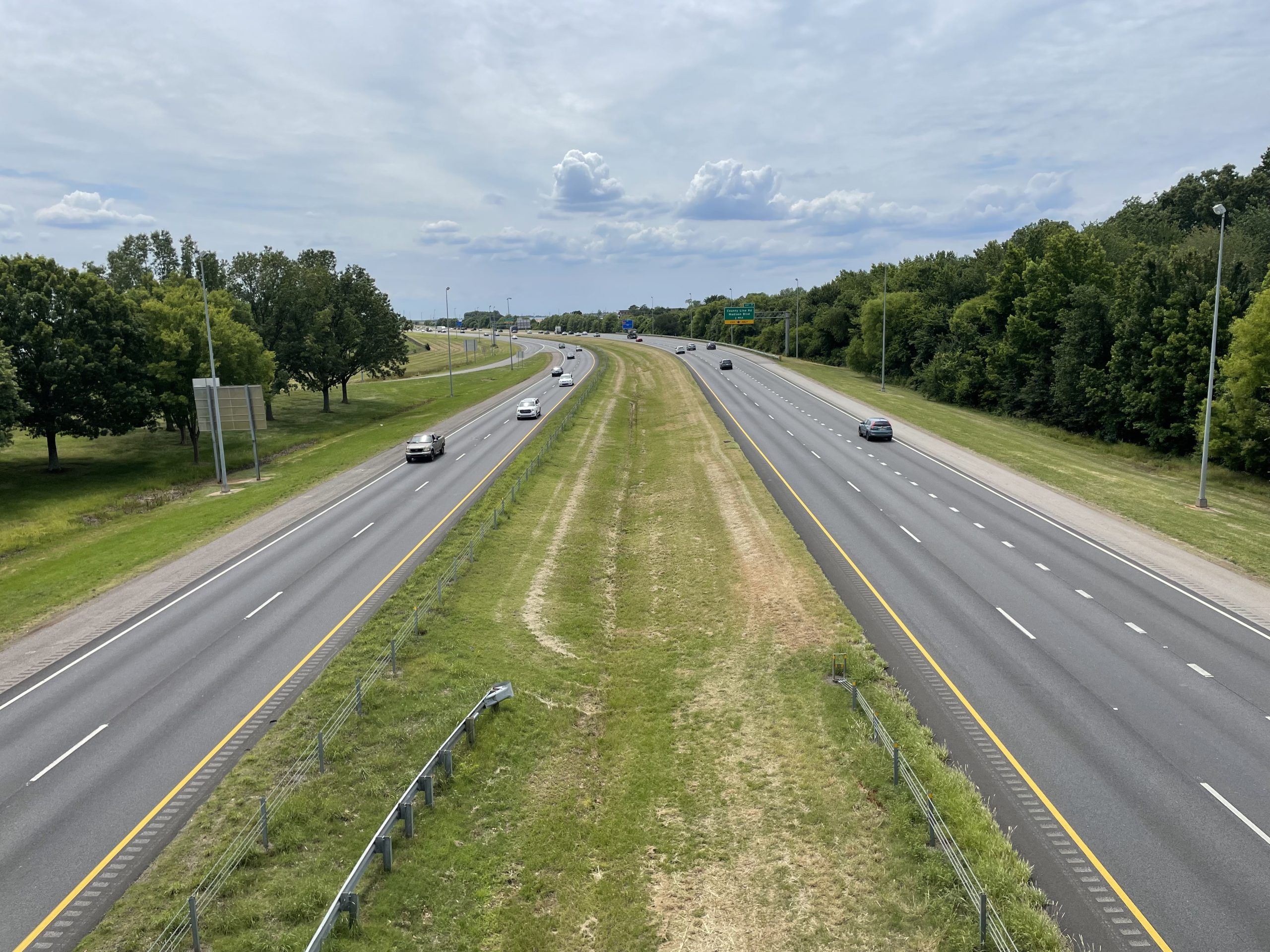 Cars travel on the four-lane segment of I-565, with eastbound and westbound roadways separated by a wide, grassy median.