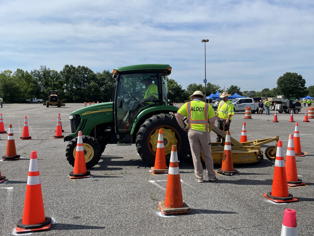 2 judges in safety vests and hard hats looking at a tractor surrounded by cones