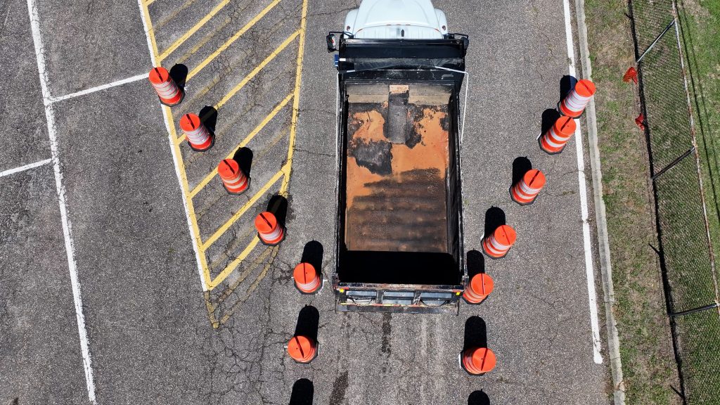 aerial view of a tandem dump truck baking into a narrow lane of cones