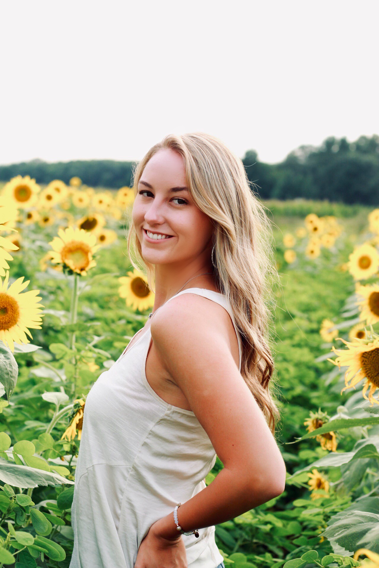 Ashlyn Huey poses for a photo in front of sunflowers.