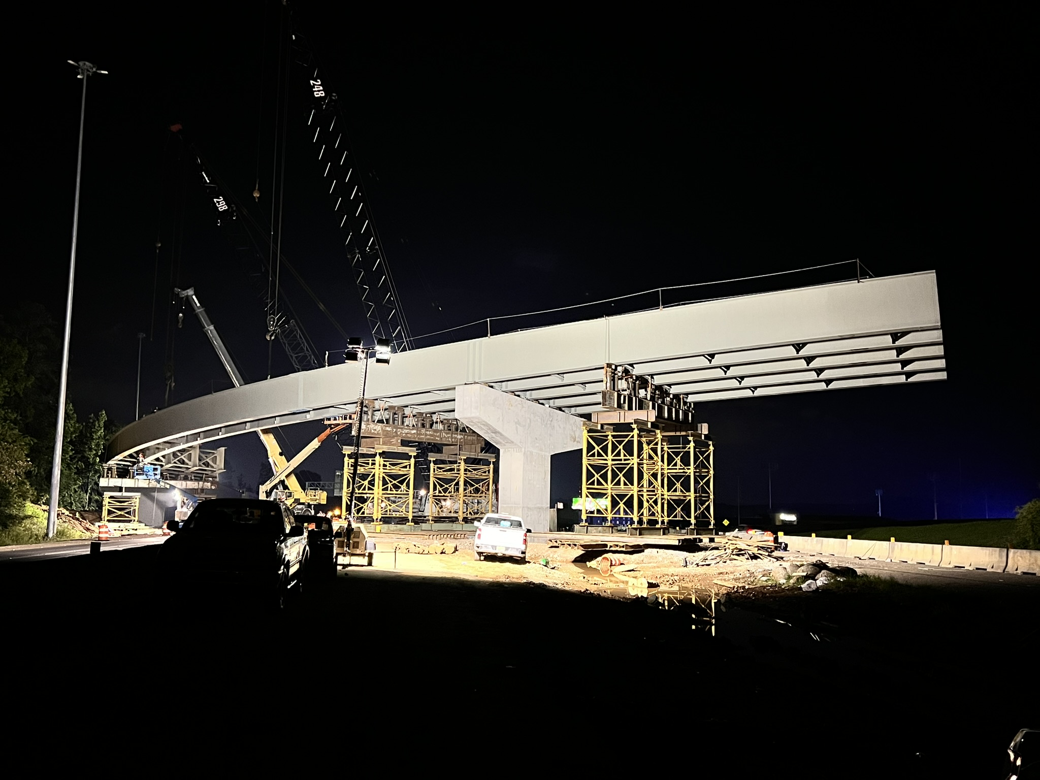 The bridge structure is well-lit against a dark background as nighttime work takes place.