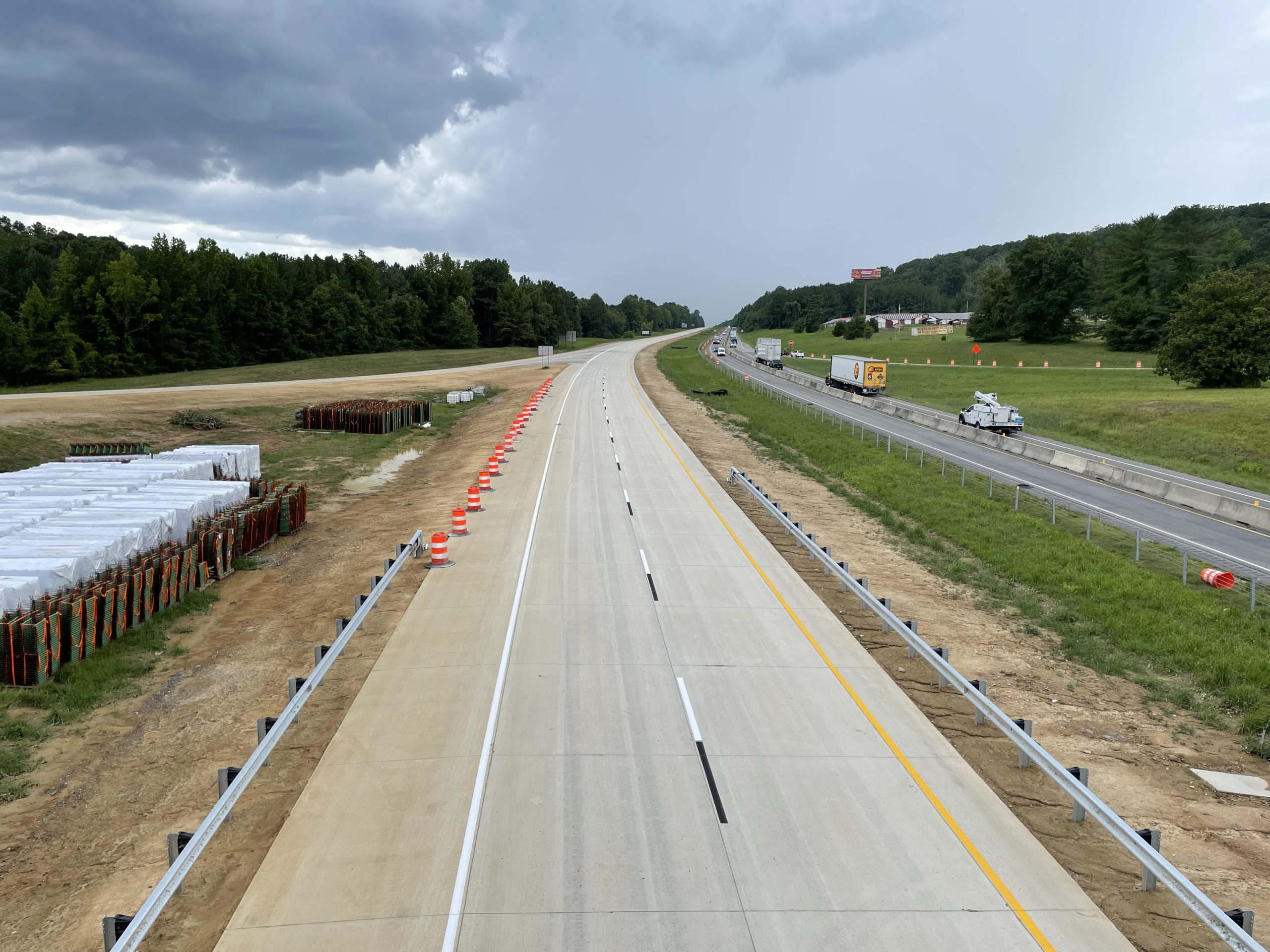 An empty concrete roadway prior to being opened to traffic. Two-way traffic can be seen on the nearby southbound roadway.