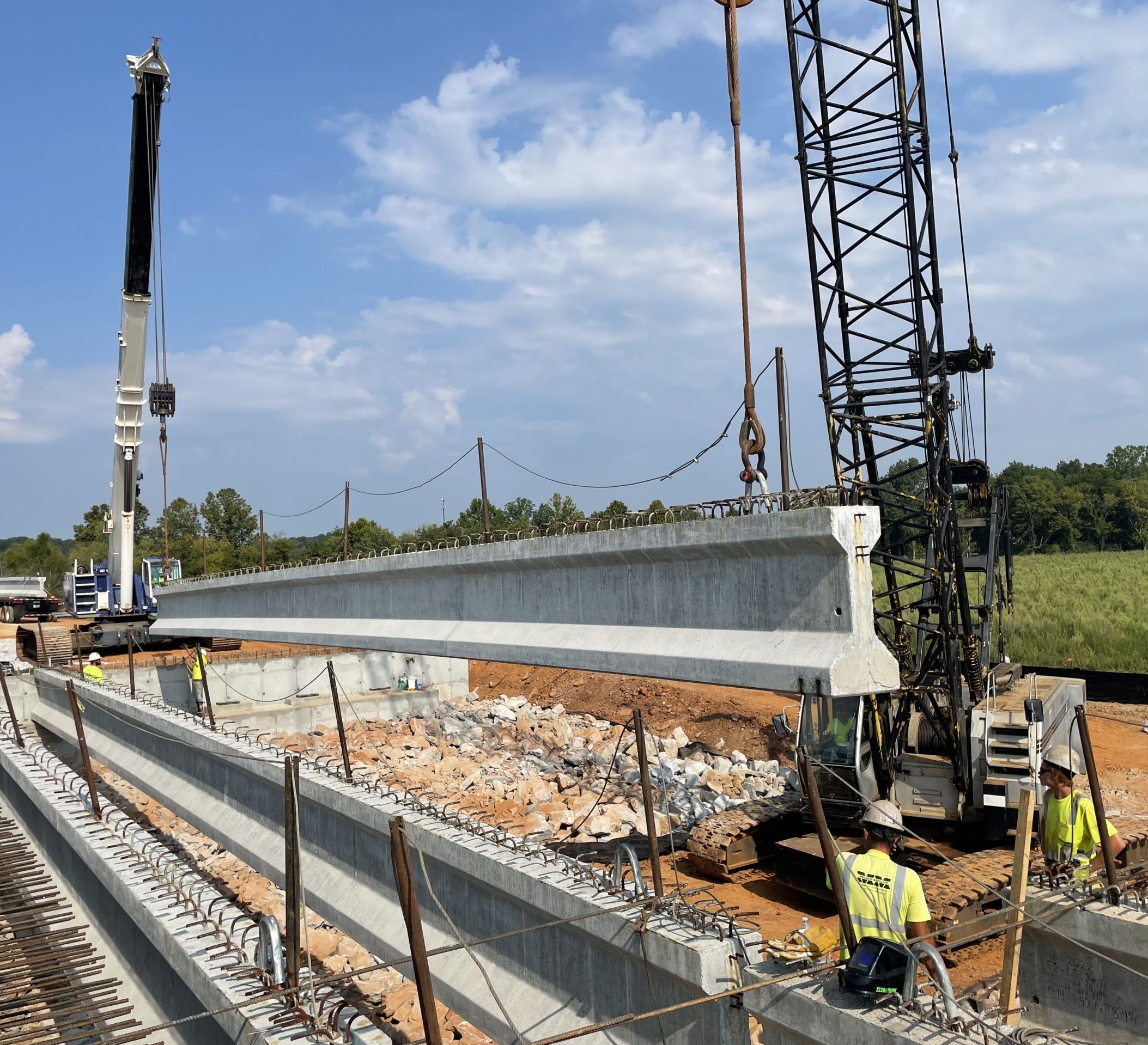 A large concrete beam is suspended from cranes