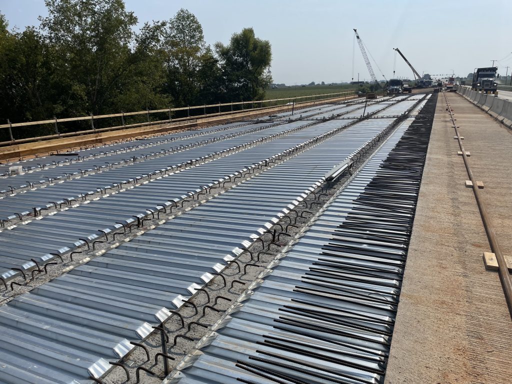 Metal forms between concrete girder. A truck in the background,