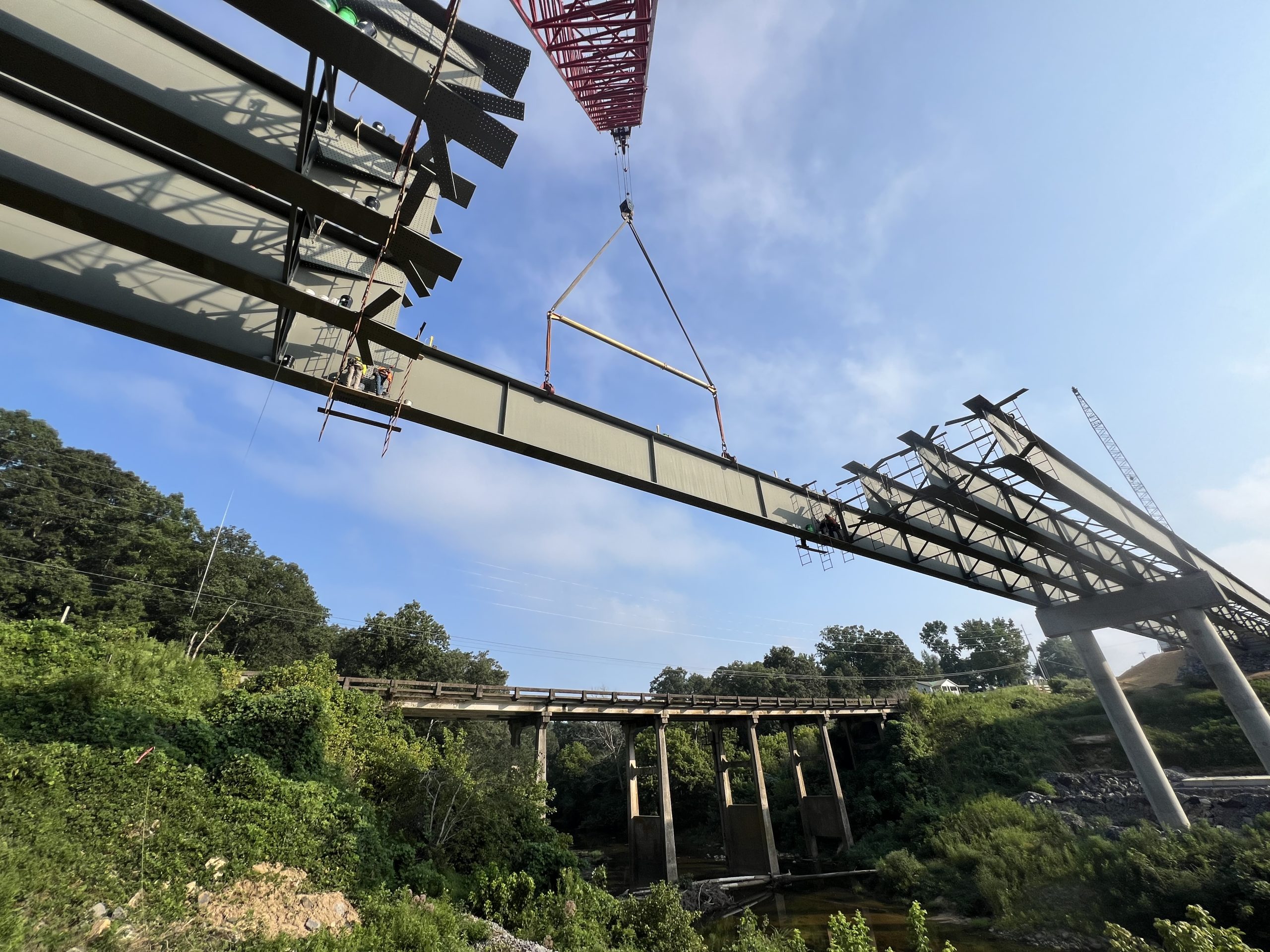 A large steel beam is suspended from a crane.