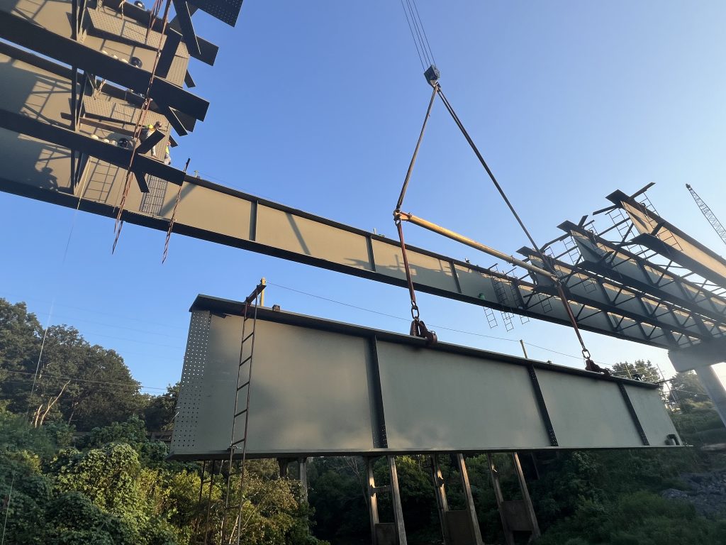 A large steel beam is suspended from a crane.