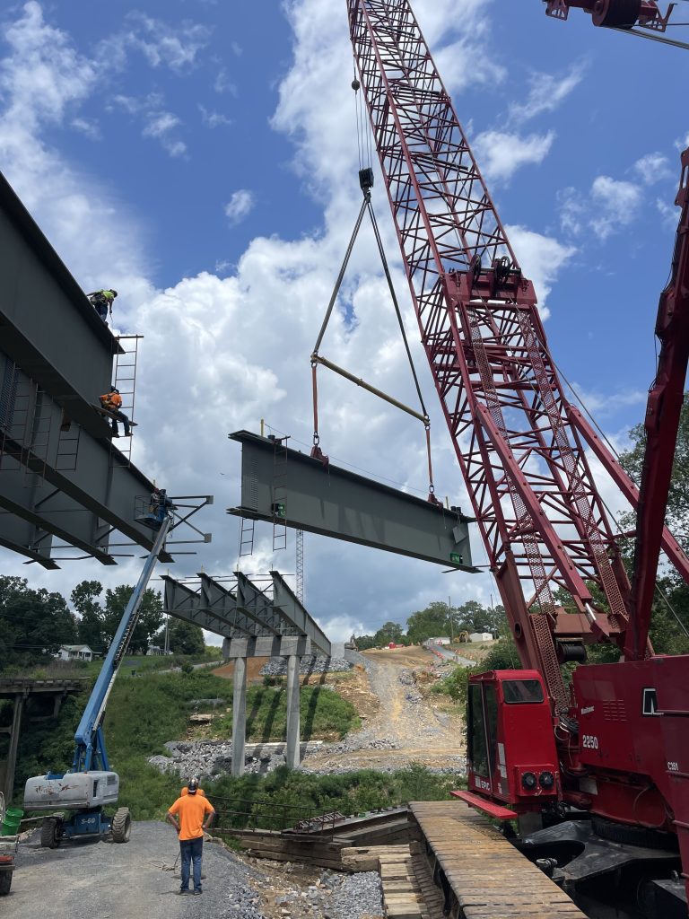 A steel beam is suspended from a crane.