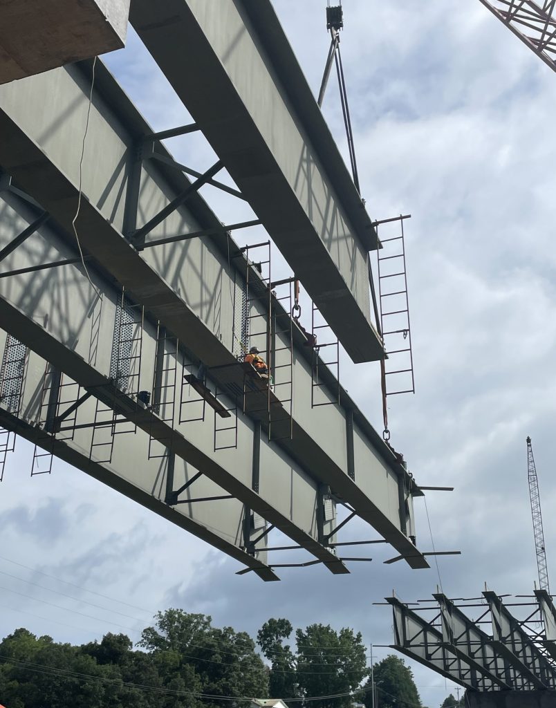 A worker works from a scaffold suspended on a girder.