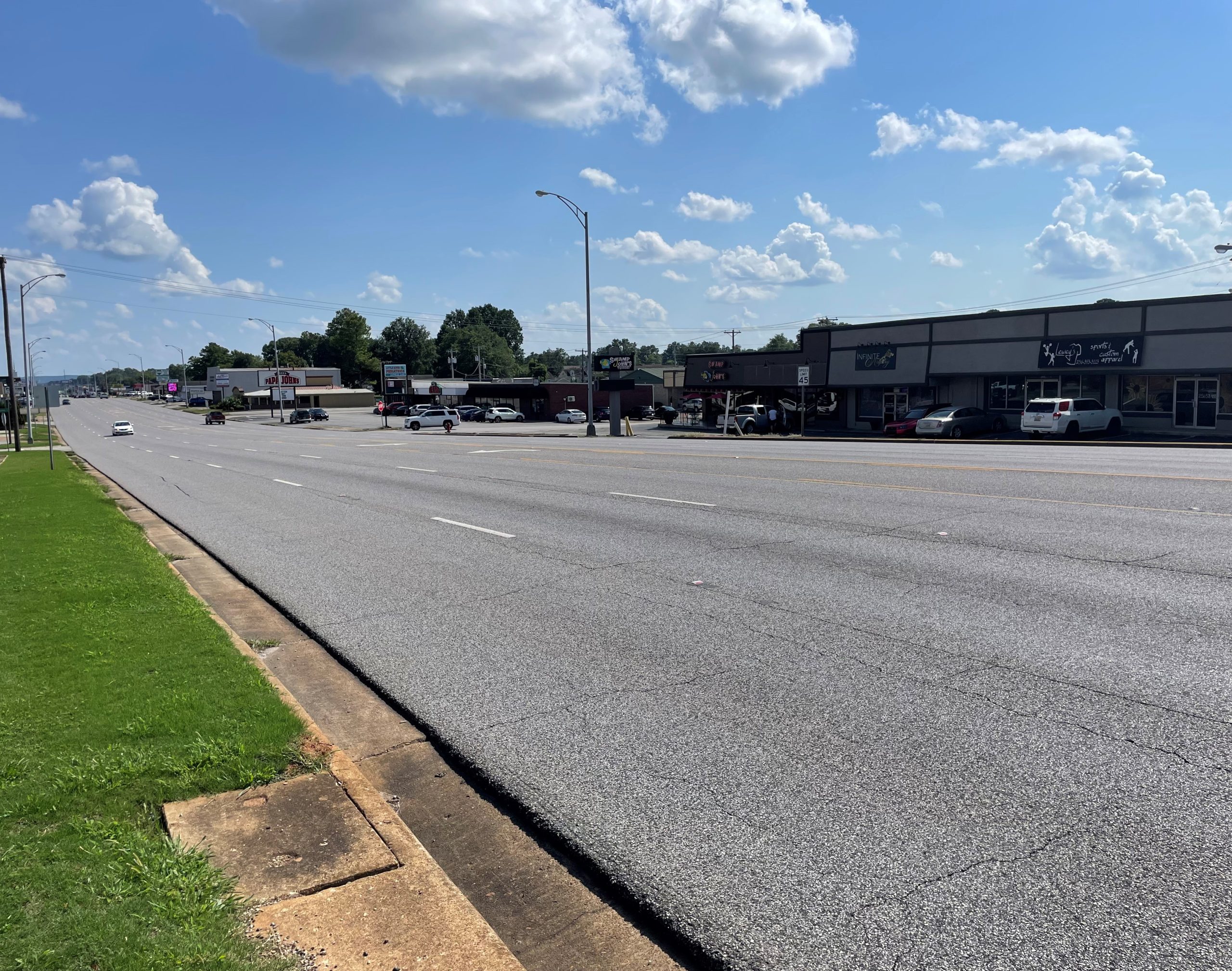 Vehicles travel on a five-lane highway with curb and gutter.