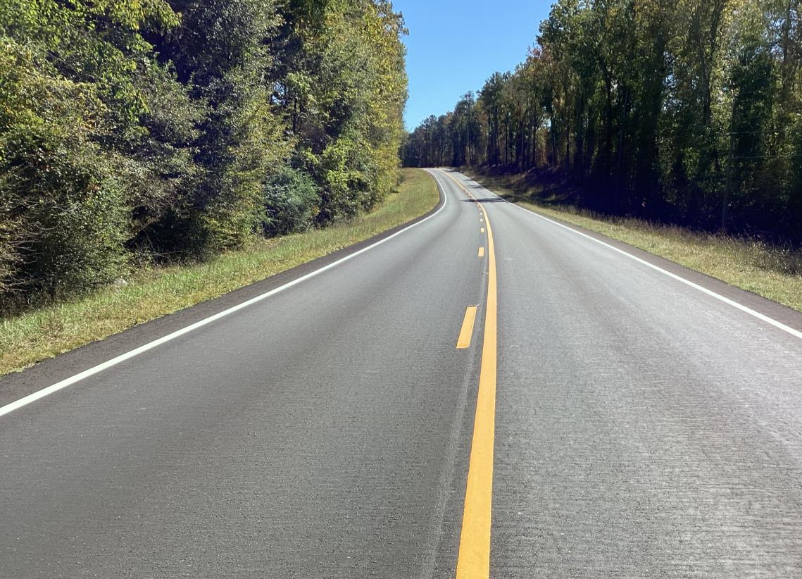 A newly maintained road with trees on either side.