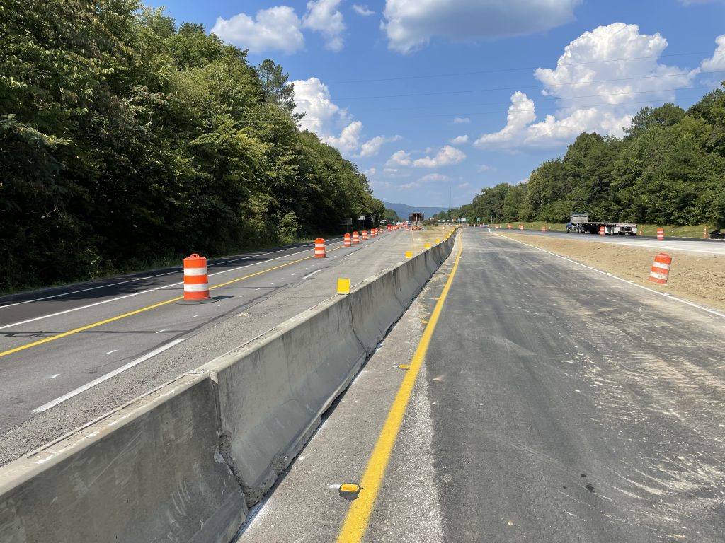 A new asphalt lane connecting two roadways, lined with concrete barrier