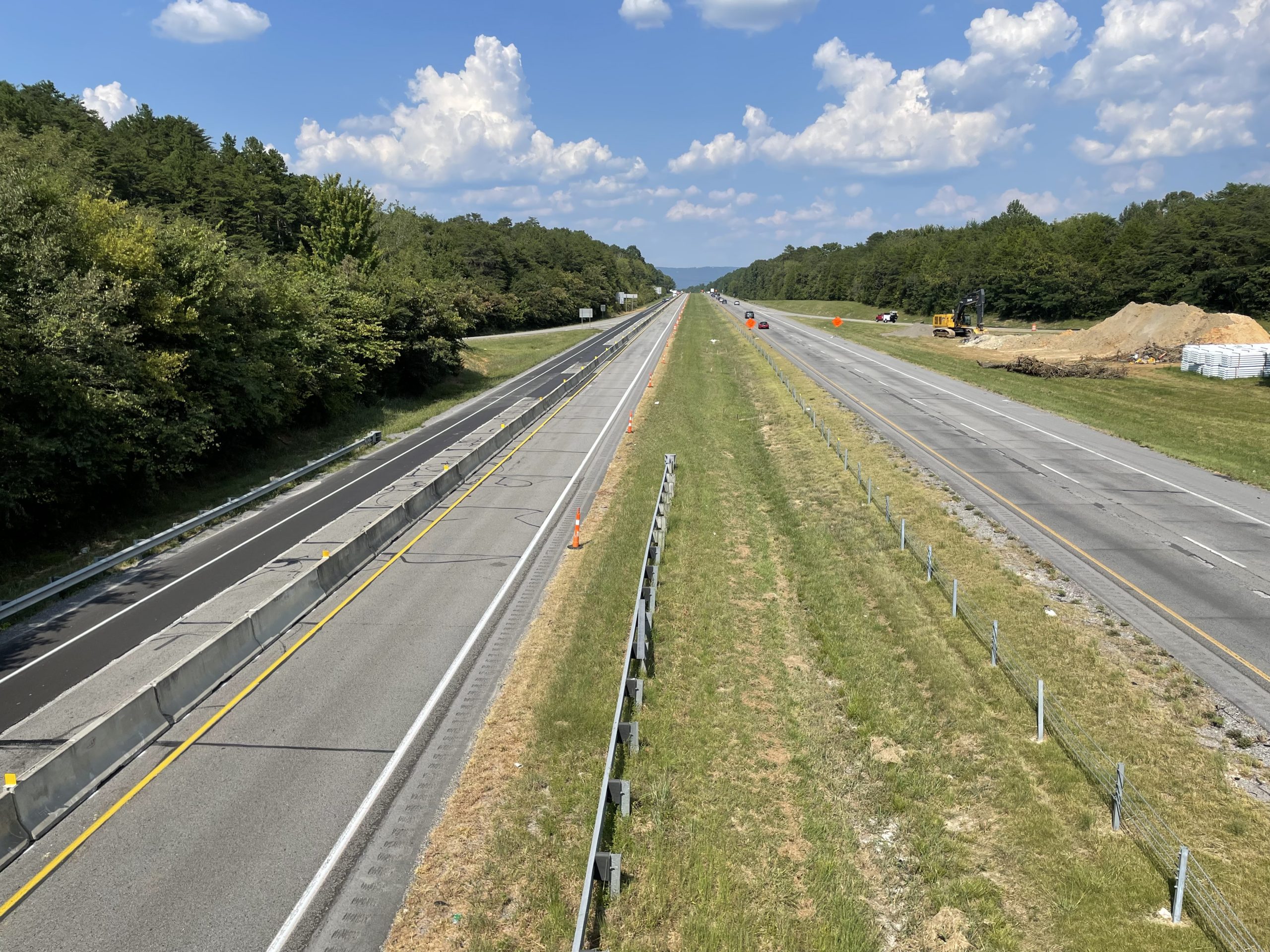 Two roadways viewed from above. On the left is the southbound roadway with concrete barrier running down the middle.