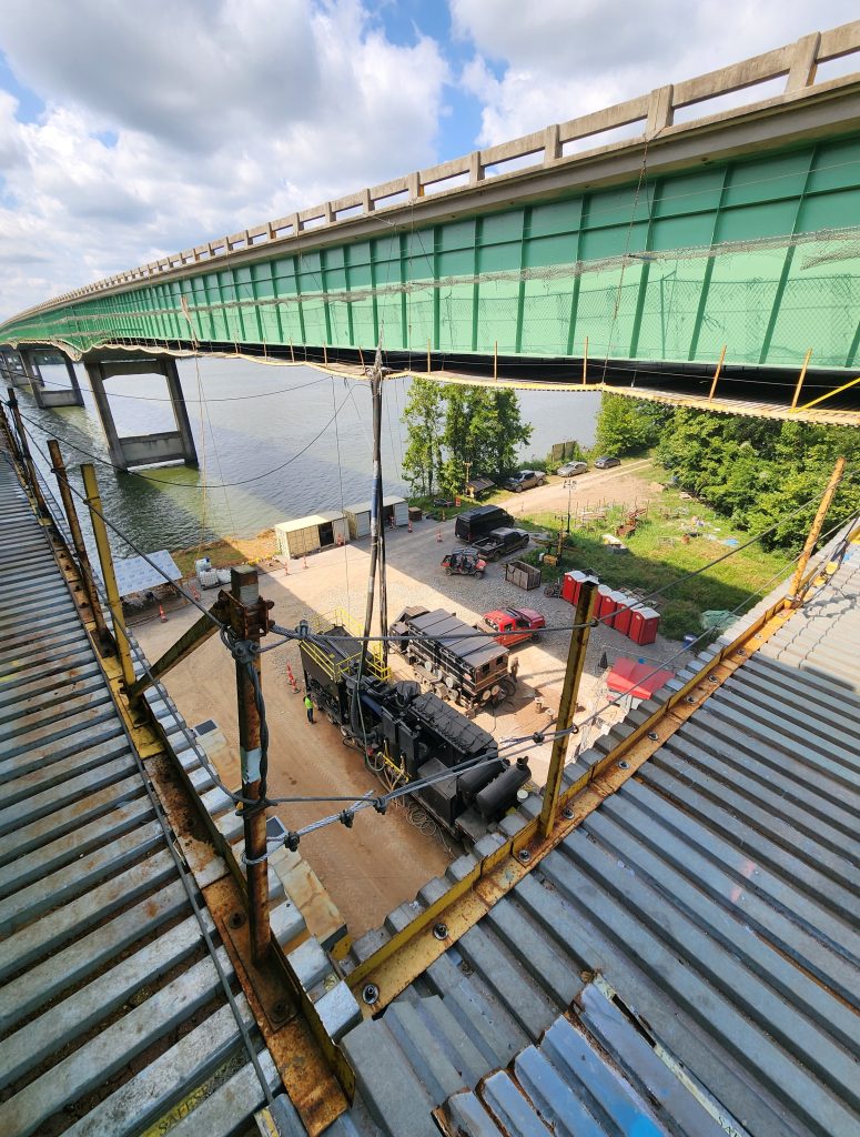 Equipment on the ground under the bridge, viewed from scaffolding above.