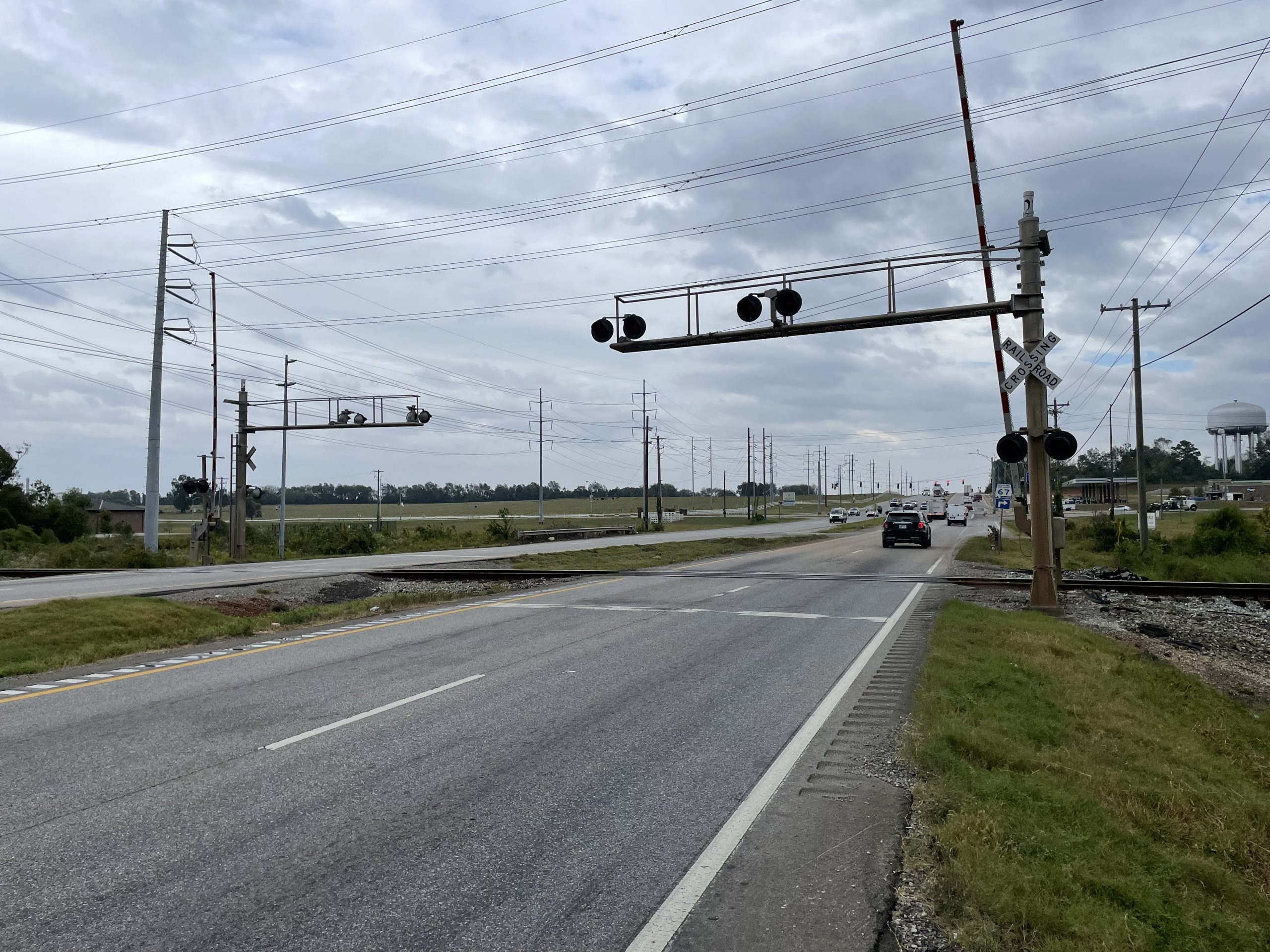 A highway crossing a railroad with lights and gates.