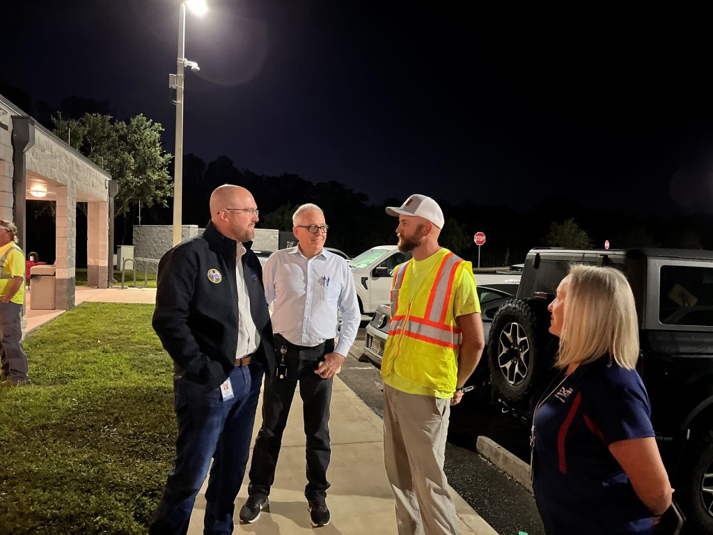 3 men and a woman standing in a semi circle talking