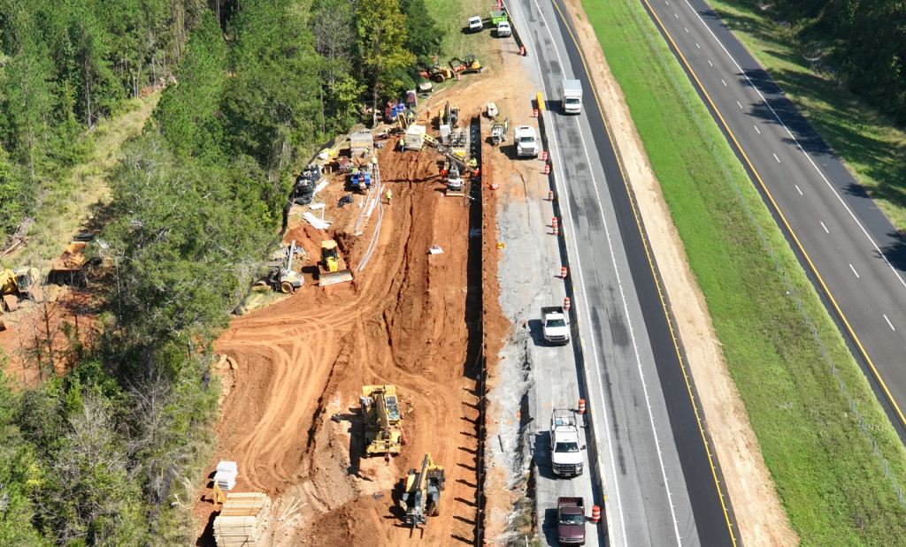 Aerial view of the construction of a soldier pile retaining wall to stabilize the shoulder and prevent further landslide activity in the area.