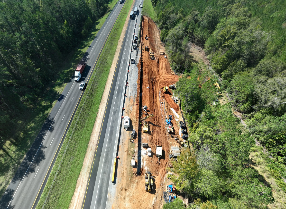 Aerial view of the construction of a soldier pile retaining wall to stabilize the shoulder and prevent further landslide activity in the area.