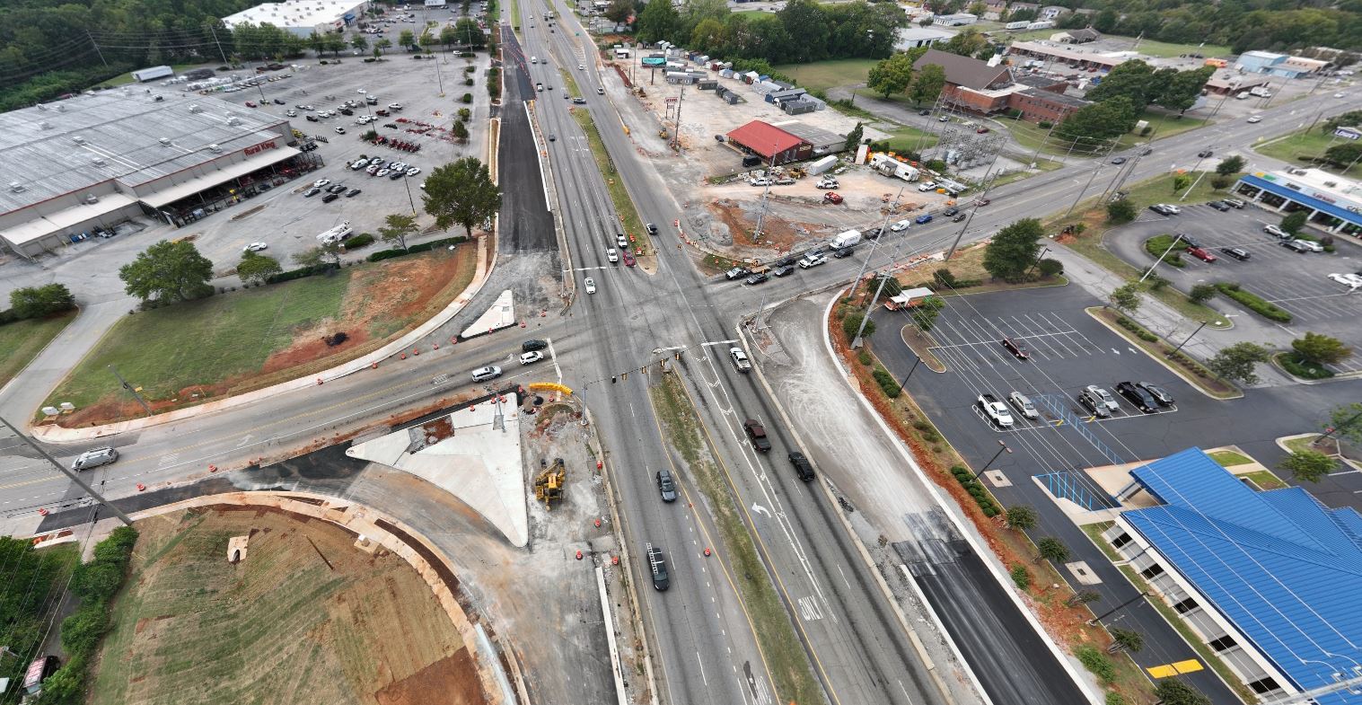 An aerial view of the intersection. Fresh black asphalt can be seen on the recently-paved service roads.