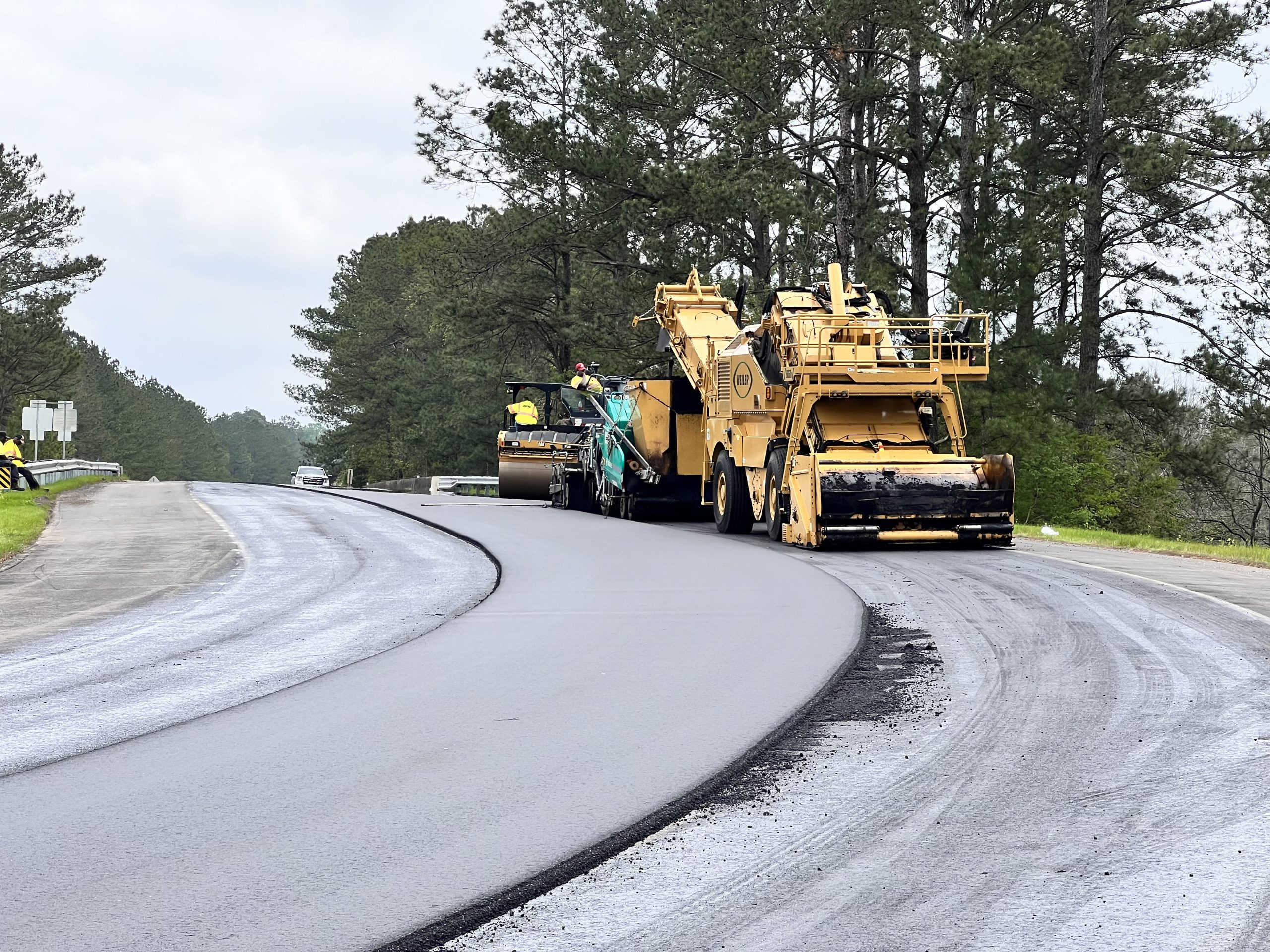 Material Transfer Vehicle (MTV) receives asphalt from the dump truck and transfers it to the paver while maintaining a consistent flow of material for uniform paving.