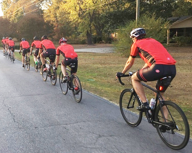 Line of people riding bicycles down a neighborhood street.