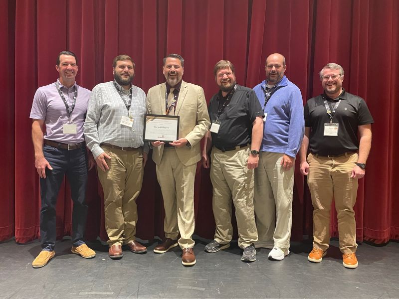 Members of the Alabama Department of Transportation and Center for Advanced Public Safety received an award on stage before a red curtain.