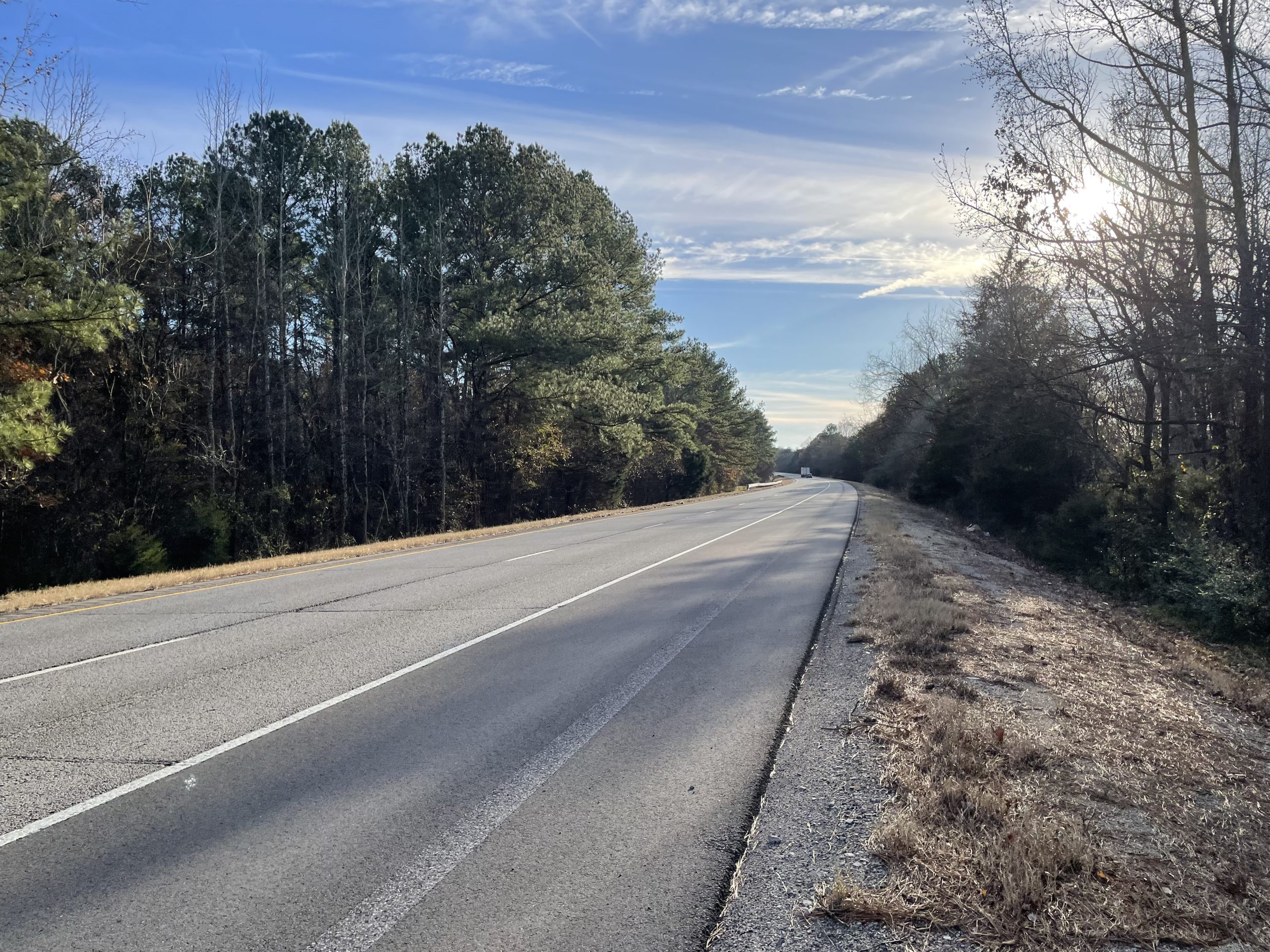 A two-lane roadway surrounded by woods