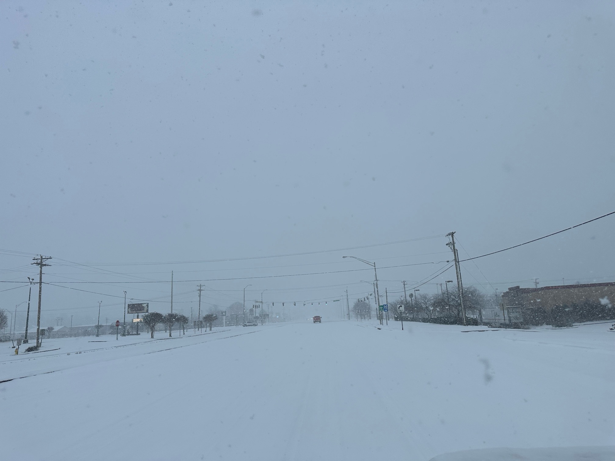 A snow covered roadway with a single truck in the distance