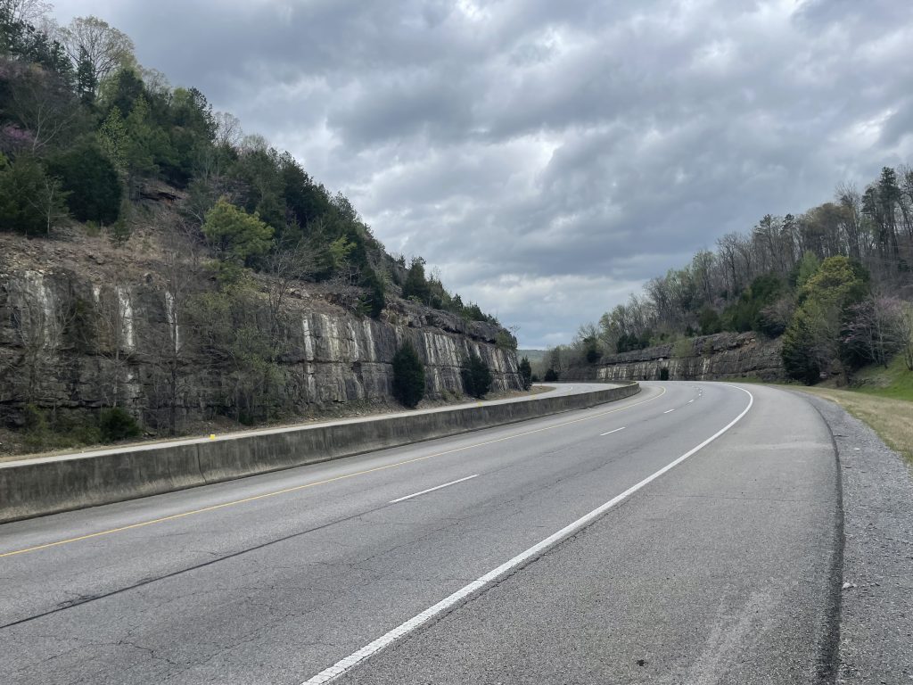 A divided four-lane highway with a concrete median barrier.
