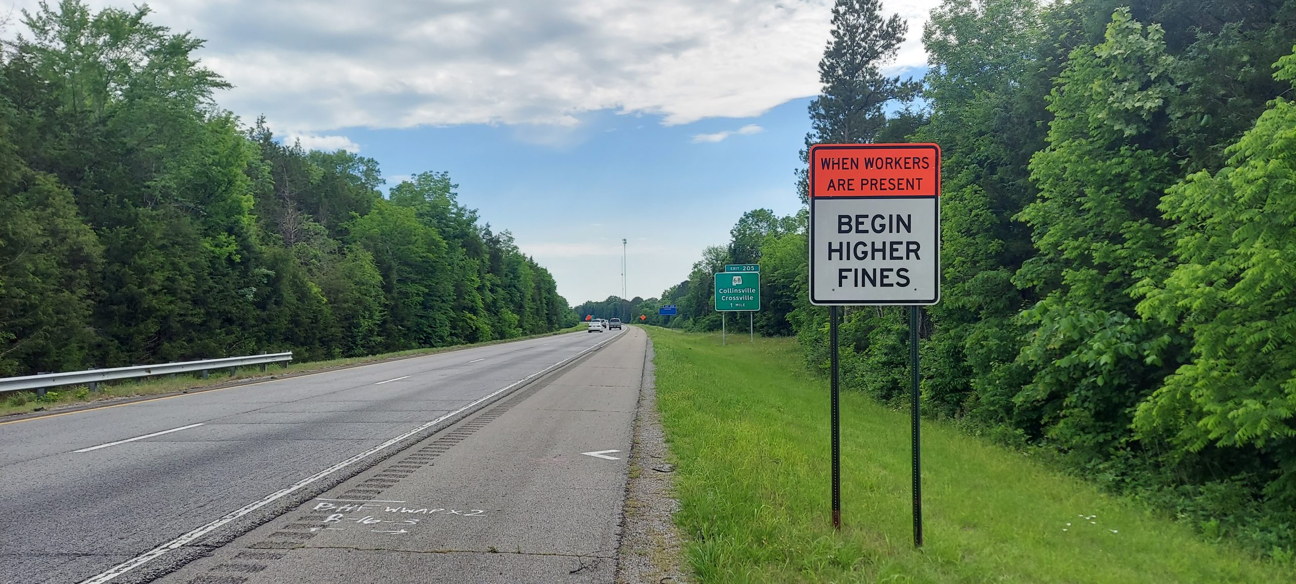 A sign reading BEGIN HIGHER FINES posted next to an interstate roadway