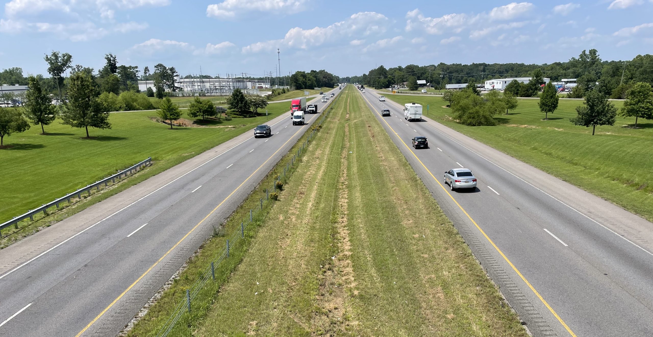 Vehicles travel on a four-lane interstate divided by a grassy median.