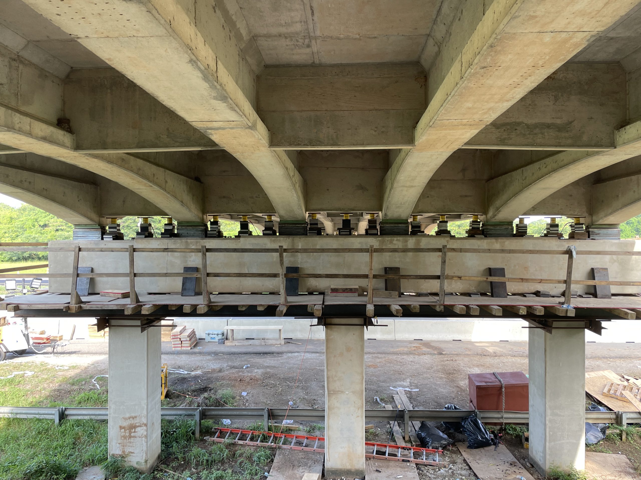 Underneath the Parker Road bridge showing raised supports and construction equipment during elevation work on I-65.