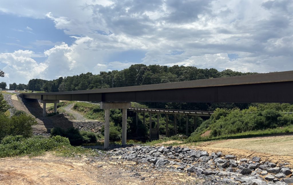 A large bridge crossing a creek between two hills.
