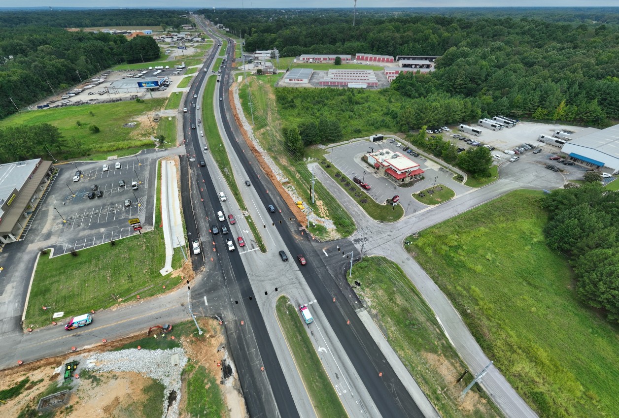 A road viewed from above. The outside lanes are visibly new pavement compared to the center lanes.