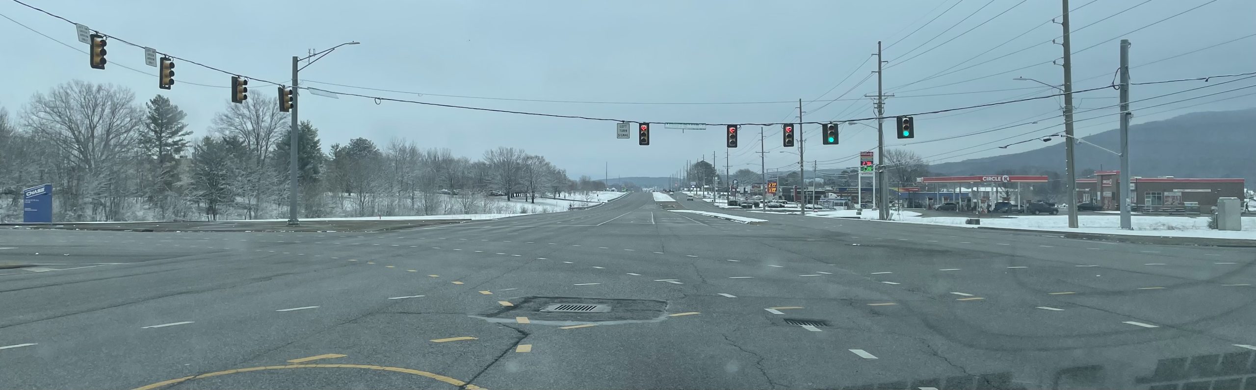 An intersection with traffic signals. Snow is on the ground.