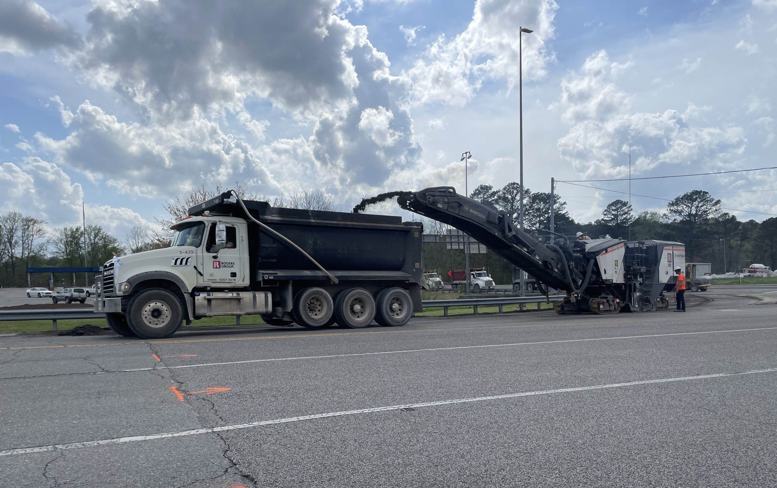 A milling machine spews millings into a dump truck