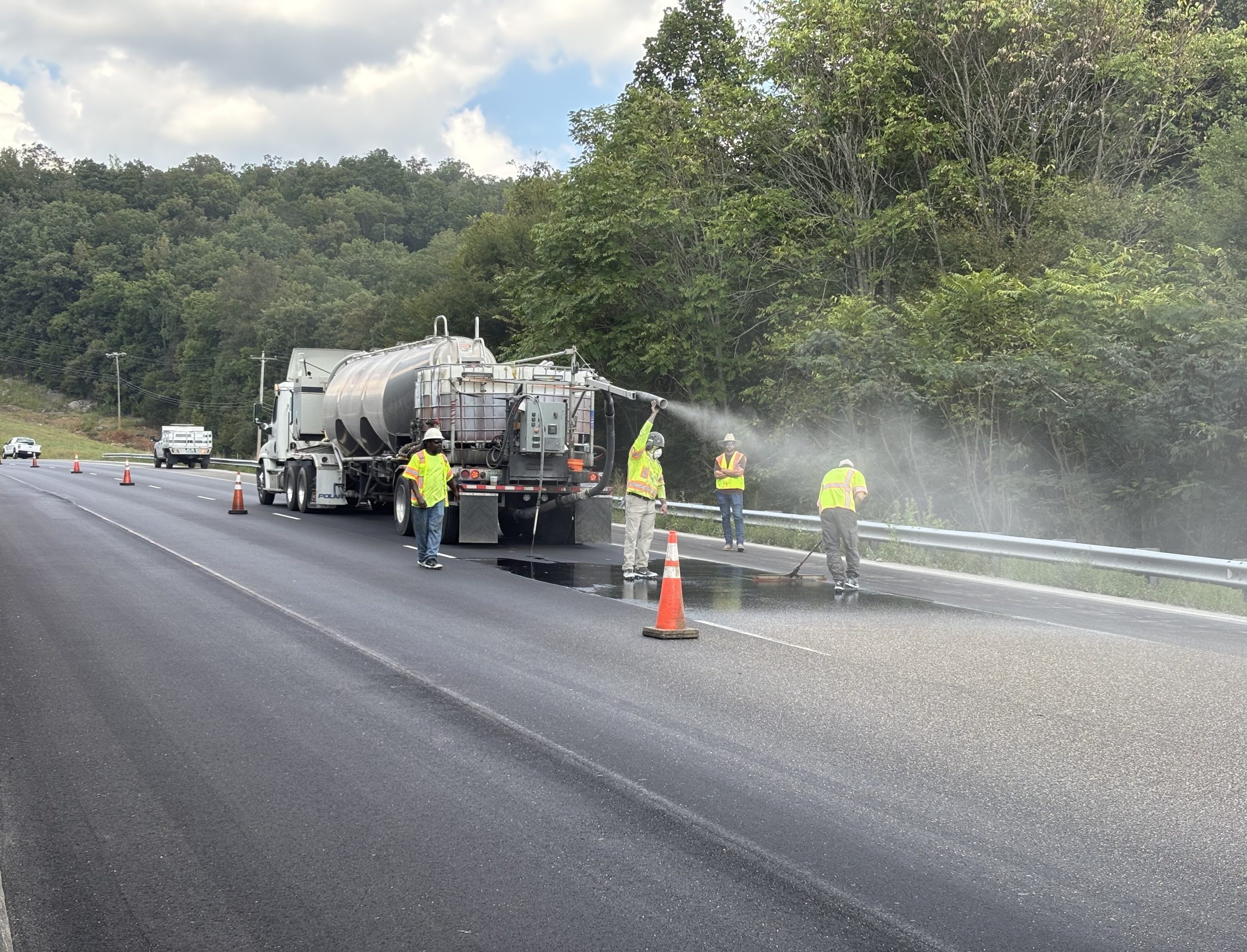 Workers spread epoxy over the asphalt pavement and cover it with aggregate