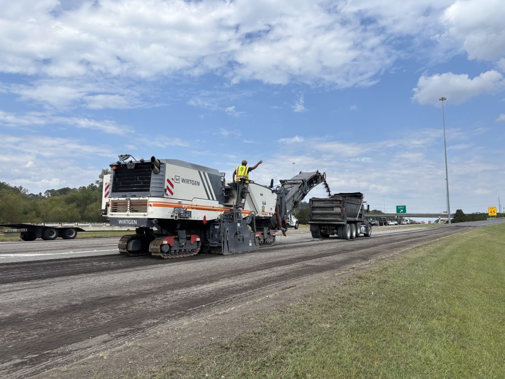 A milling machine leaves a finely grooved roadway behind as it removes the old road surface.
