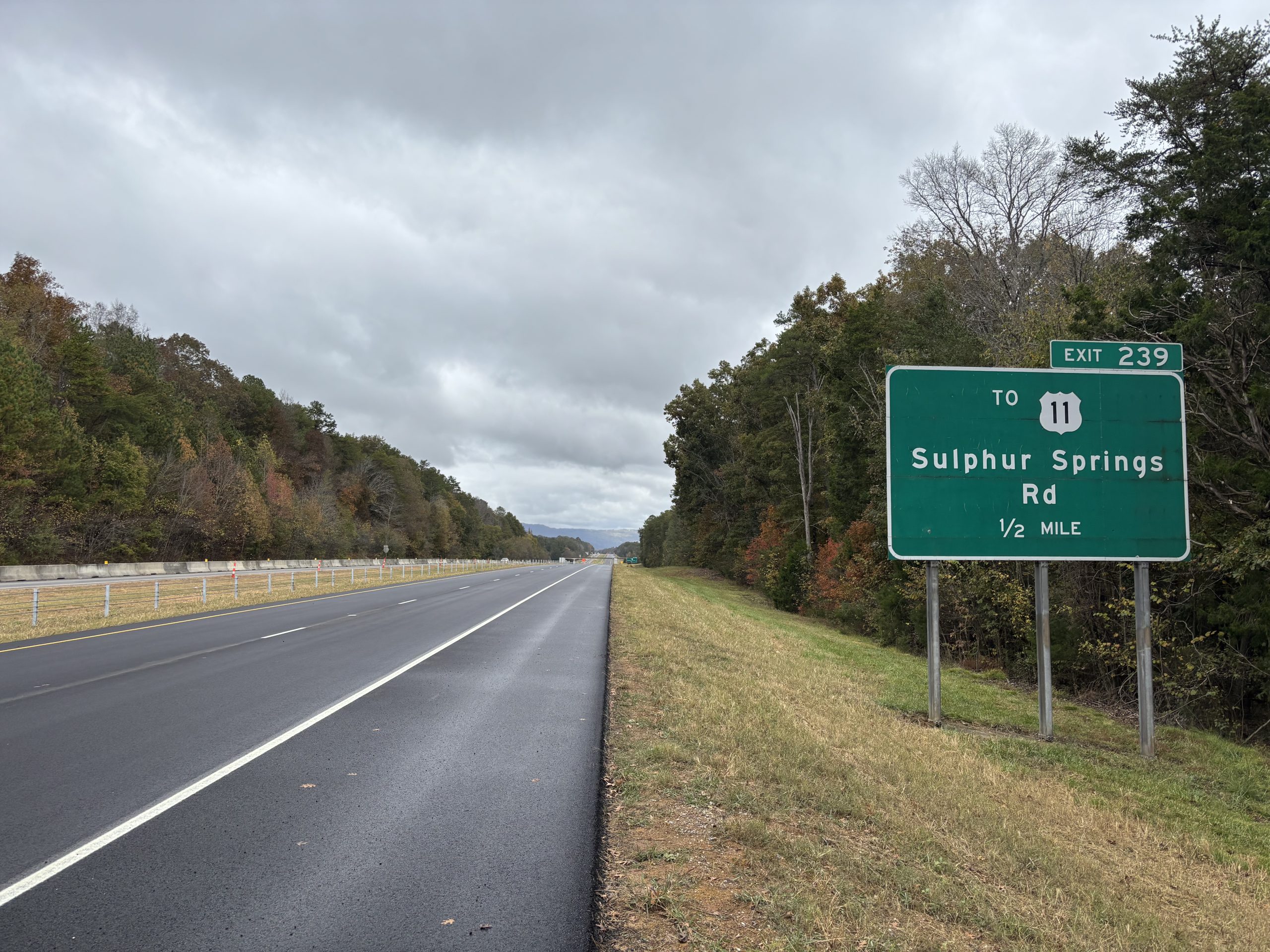 An exit sign for Sulphur Springs next to a new asphalt roadway