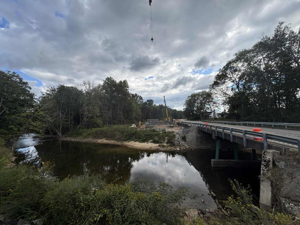 A creek under an old bridge. A crane looms on the far bank.