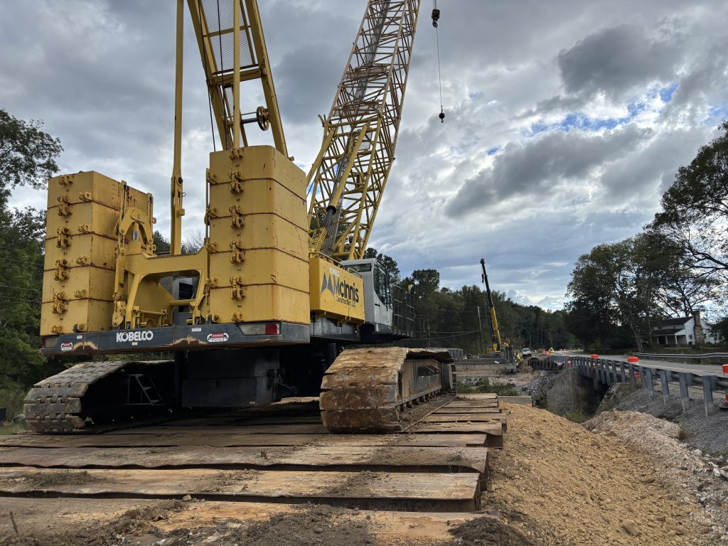 A crane in the foreground with a bridge in the background