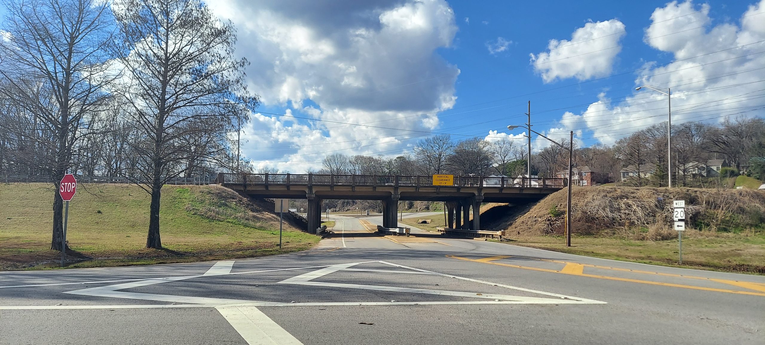 An aging bridge carries a larger highway over a two-lane road.