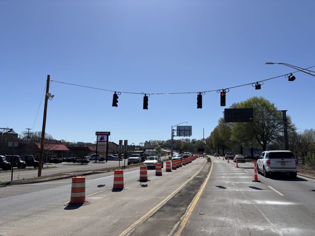 A turn signal on a cable just south of the Mitchell Boulevard bridge. The highway is reduced to one lane in each direction by concrete barriers, drums, and cones.