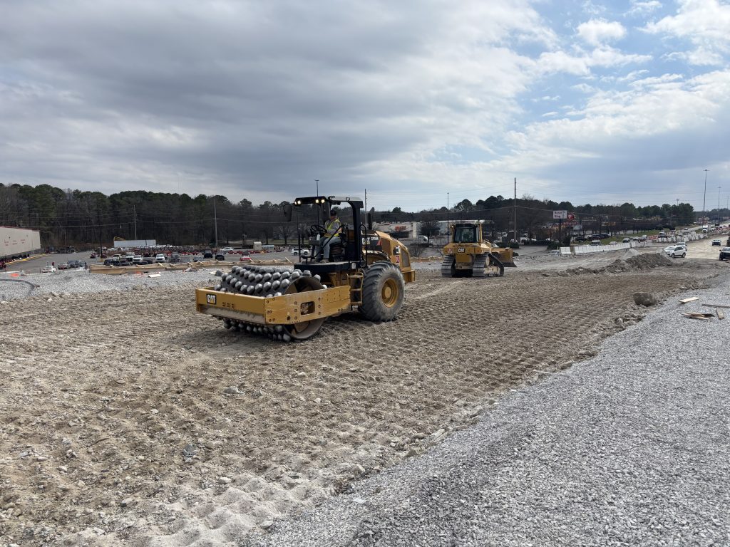 A roller and a bulldozer work on a slope.