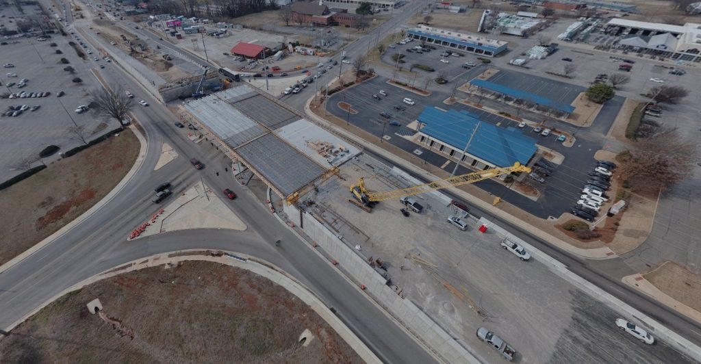 An aerial view showing a crane north of the bridge and construction of the bridge deck.
